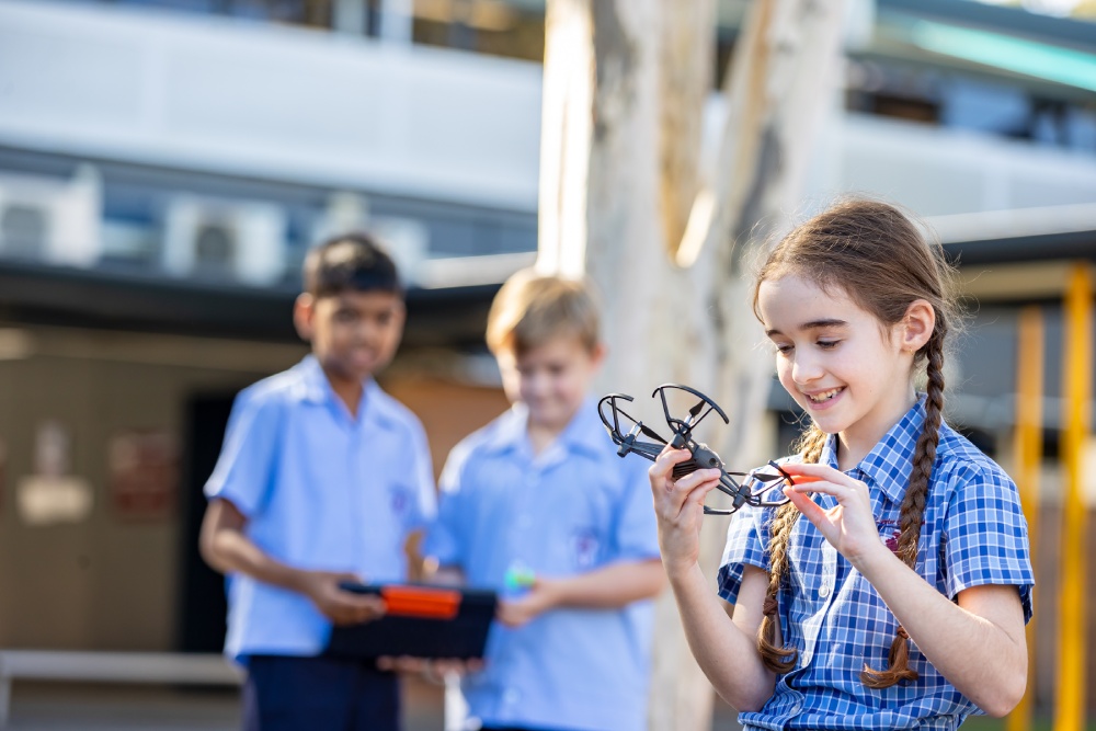 Student examining a Drone object while classmates observe, highlighting curiosity, creativity and learning through making