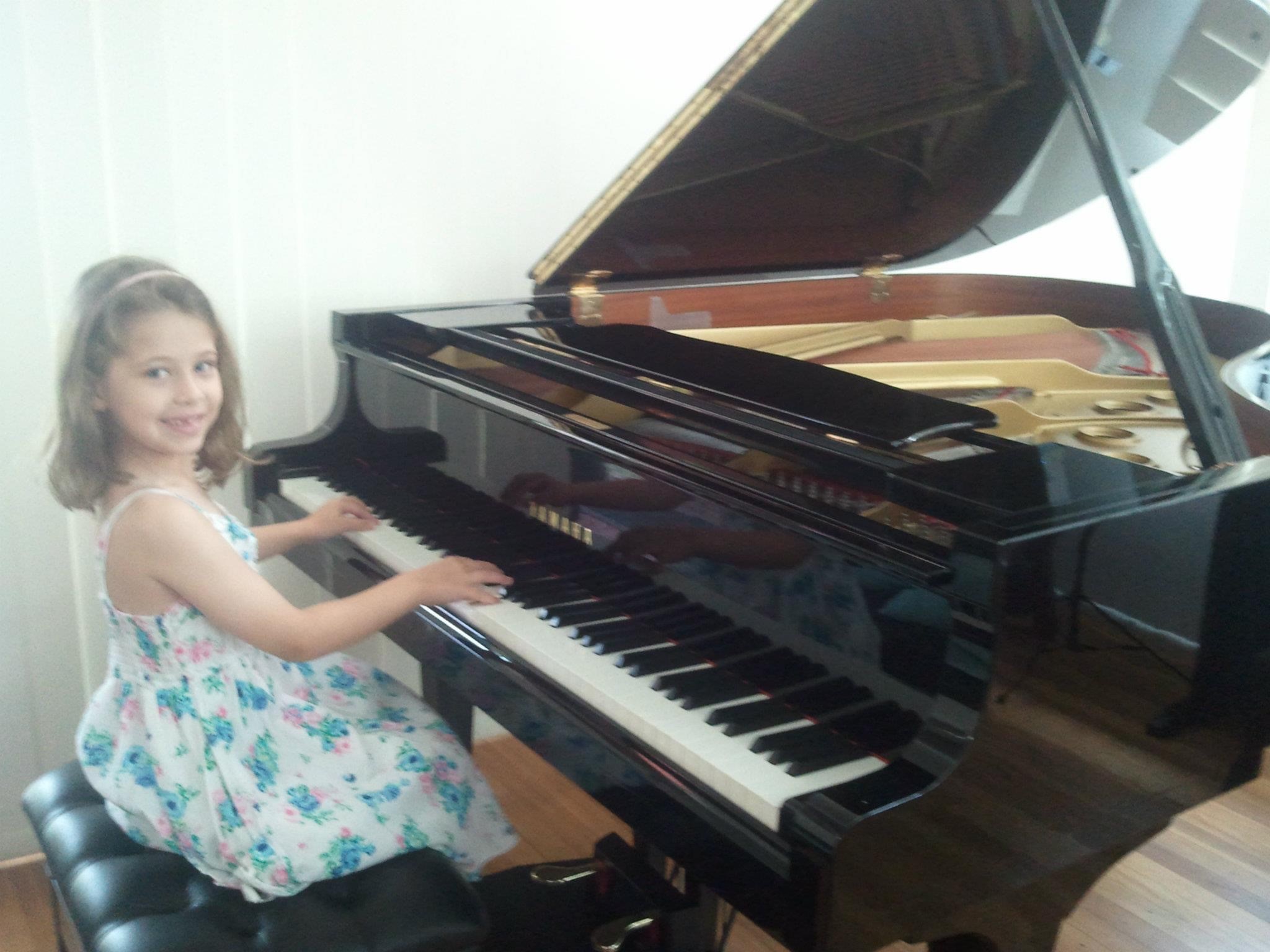 Child playing a grand piano, highlighting early music learning, creativity and engagement with instrumental performance