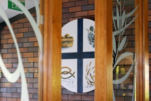 Decorative door panel featuring a Christian cross with symbolic images, highlighting Catholic faith, tradition and identity within the school community