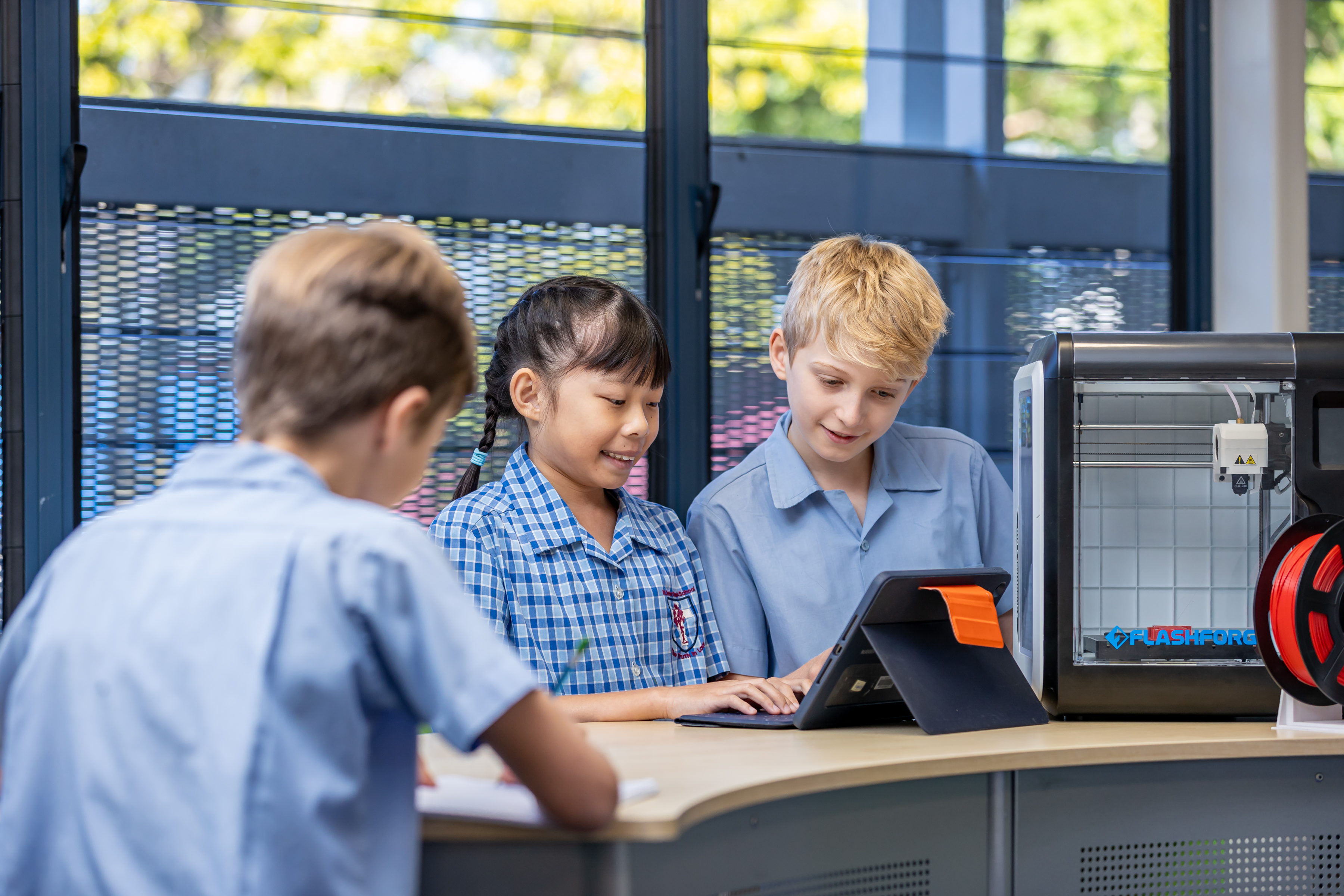 Students collaborating with a tablet and 3D printer, highlighting hands‑on STEM learning, problem solving and future‑focused inquiry in the classroom