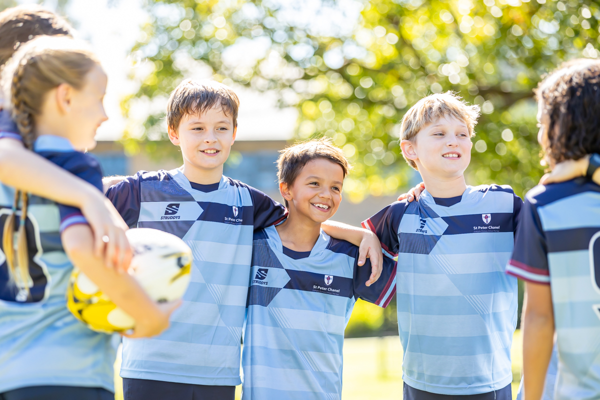 Students standing together in school sports uniforms with arms around each other, highlighting teamwork, friendship and pride in school sport