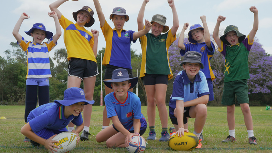 Students standing together on the school oval holding sports balls, highlighting teamwork, participation and enjoyment in school sport