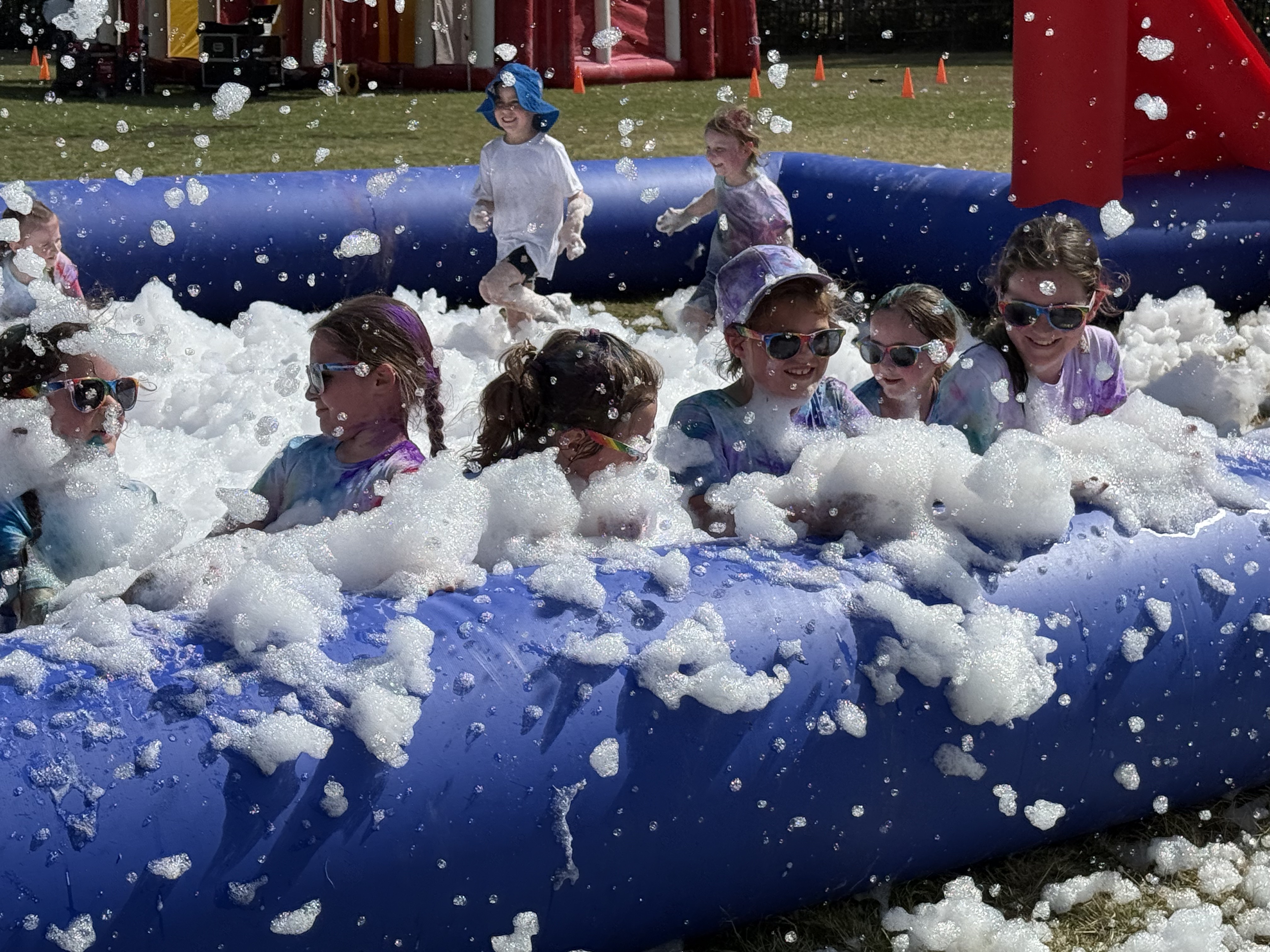 Students playing together in a foam obstacle area, highlighting teamwork, enjoyment and inclusive participation in the Colour Run