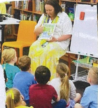 Educator reading to a group of children during a story session, highlighting early literacy, listening and shared learning