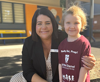 Prep student standing with a staff member on school grounds, highlighting a welcoming start to learning and positive transition into the early years at St Peter Chanel Primary School