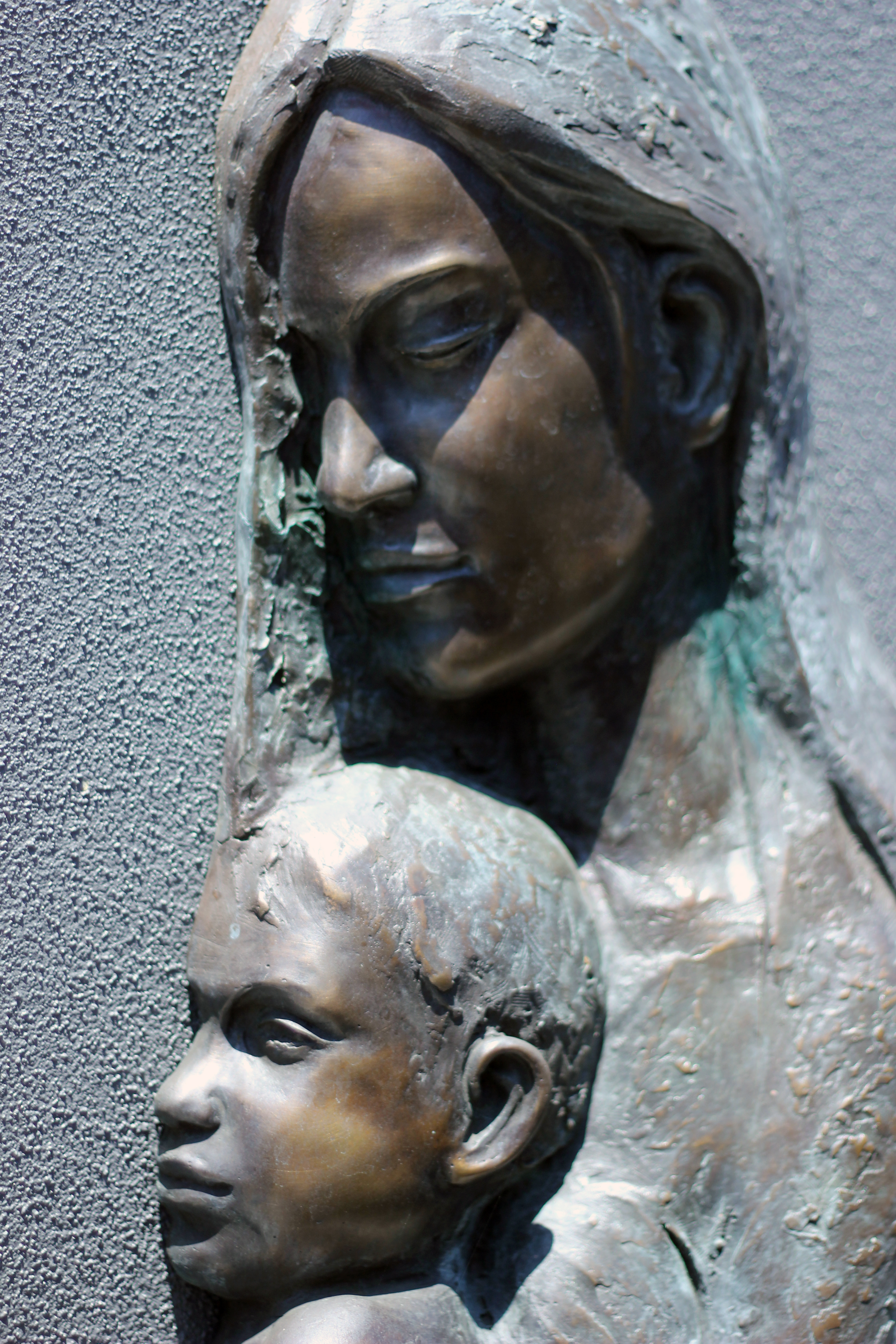 Sculpture of a caregiver holding a child, representing care, protection and nurturing relationships within a faith‑based school community