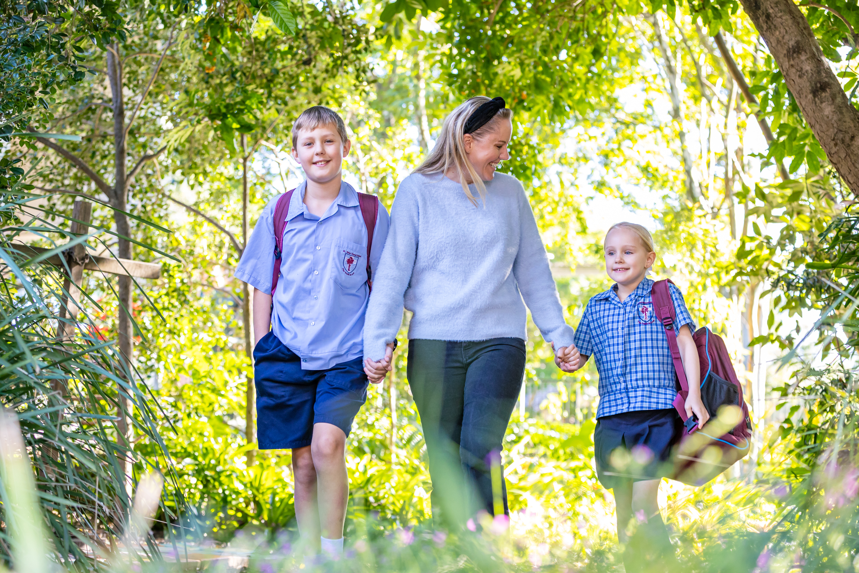 Students walking to school with a family member along a leafy pathway, highlighting care, connection and a supportive school community at St Peter Chanel Primary School