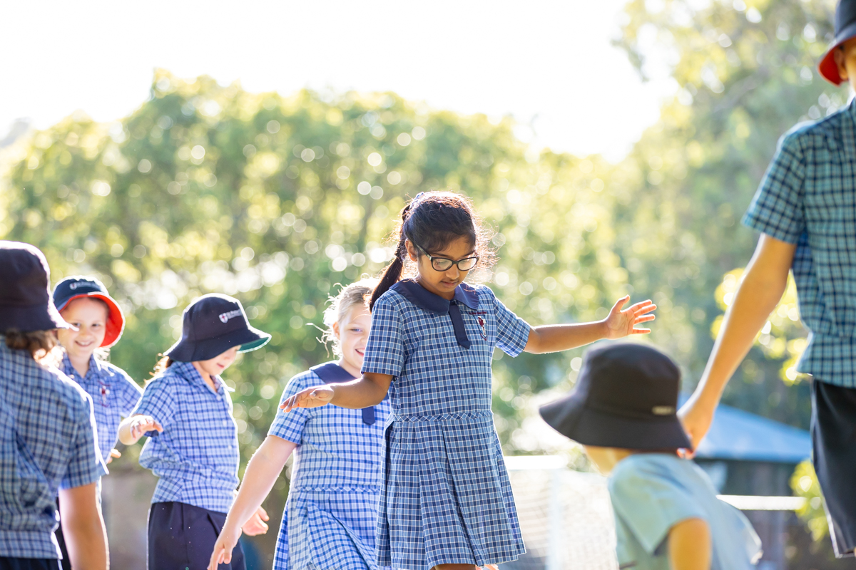 Students playing together outdoors in school uniform, highlighting active play, balance and enjoyment within a supportive primary school environment