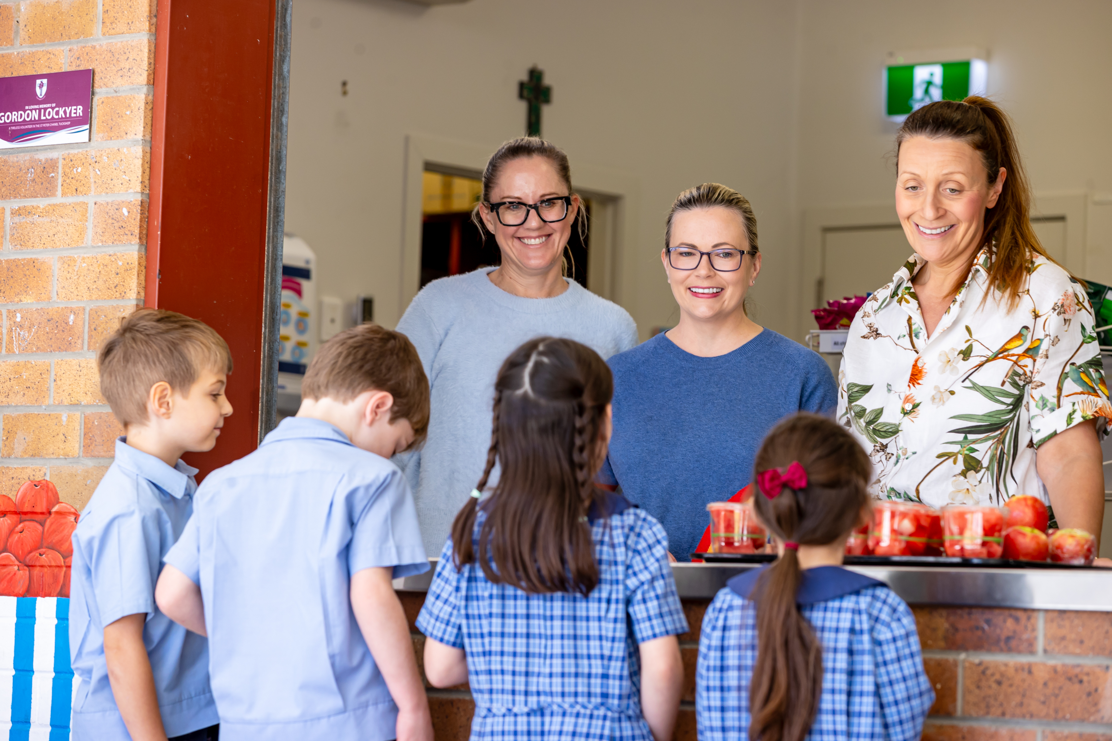 Students being served food by staff at the school tuckshop, highlighting healthy choices, daily routines and supportive care within the school community
