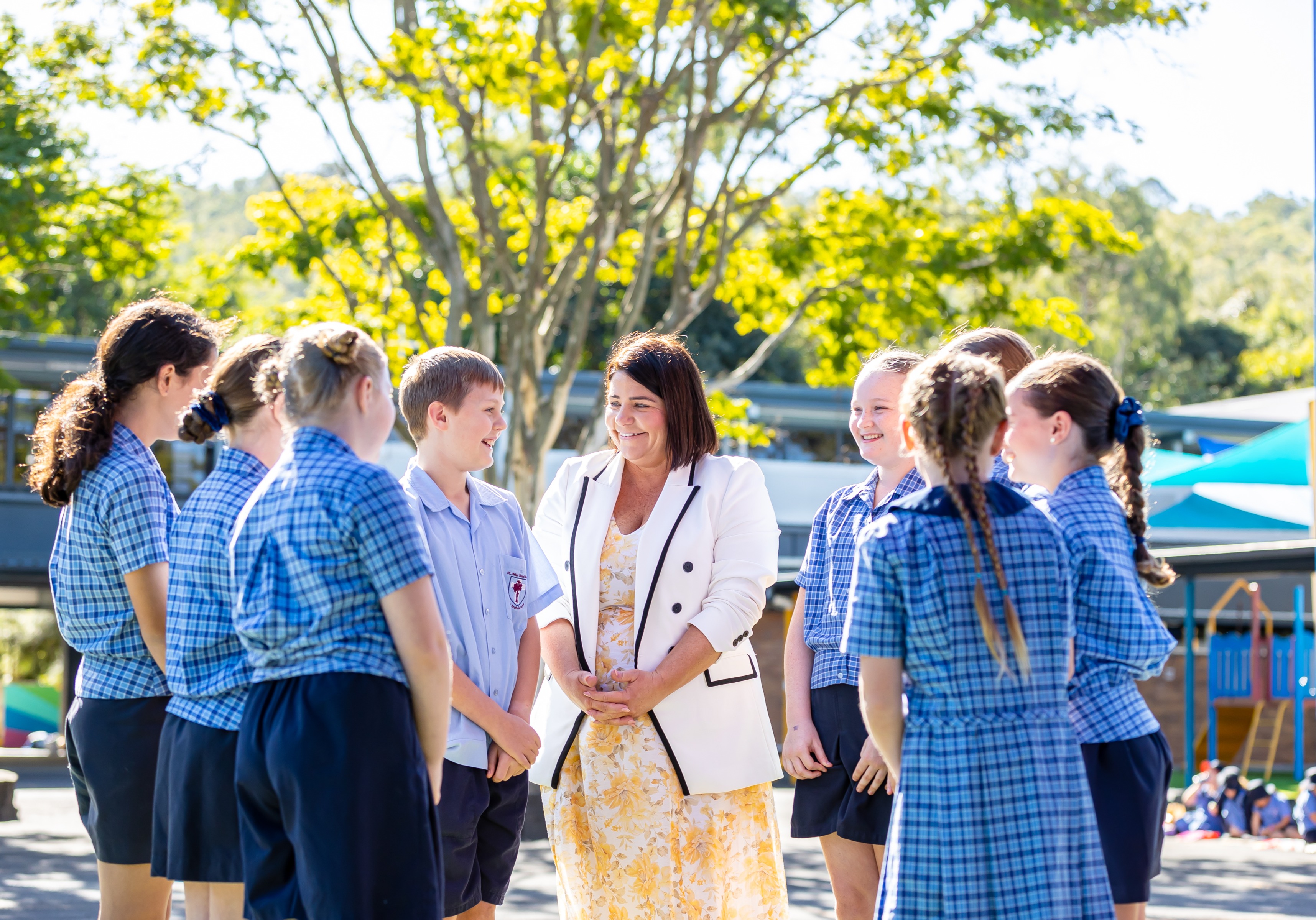 Principal Bec O’Connor standing with students on school grounds, highlighting approachable leadership, student voice and a connected school community at St Peter Chanel Primary School